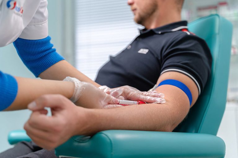 Медсестра берёт кровь из вены у пациента в процедурном кабинете клиники АлкоСпас